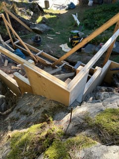 Plywood and timber formwork built between uneven rock faces.