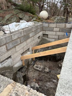 Inside the masonry root cellar with block walls and exposed rock floor.