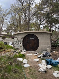 Natural stone being installed around the root cellar's round door.