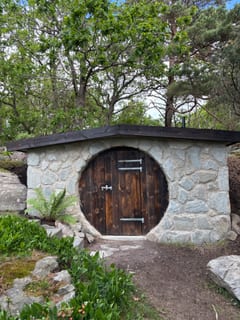 Masonry root cellar viewed straight on with planting around the entrance.